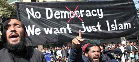 A crowd of Muslim men protesting with signs: No democracy, we just want Islam.