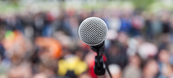 A microphone in front of a crowd as if one were telling their story and giving testimony to Jesus as their Savior.