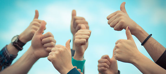 A group of hands with thumbs up with a lightly cloudy blue sky in the background. Inspire and enrich spiritual life.