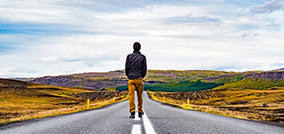 A man walking down a paved road in the desert. Miracles highlight the limitless possibilities of God's power and His love.